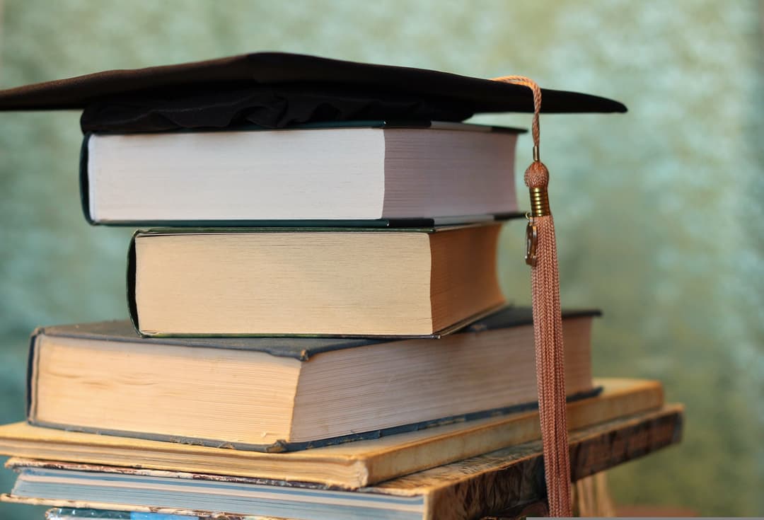 Ein Stapel Bücher mit einem schwarzen Doktorhut obenauf